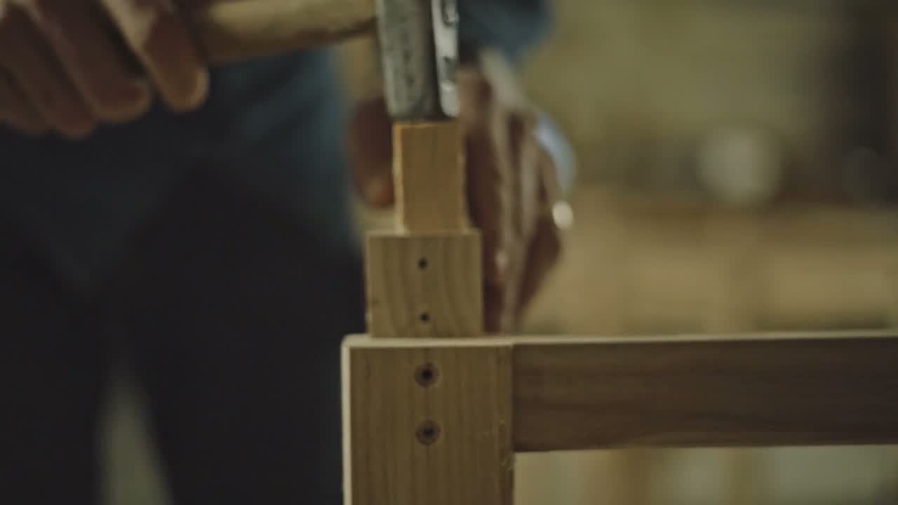 Ein Zapfen wird mit dem Klüpfel in die Holzverbindung getrieben
